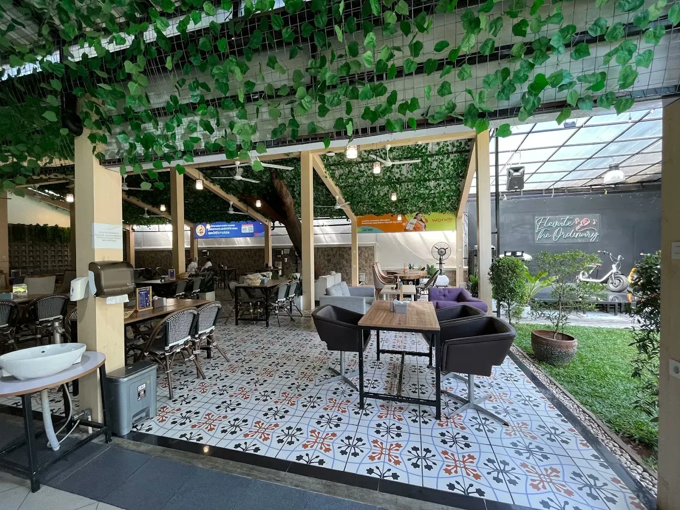 Lounge semi-outdoor dengan sofa dan meja panjang