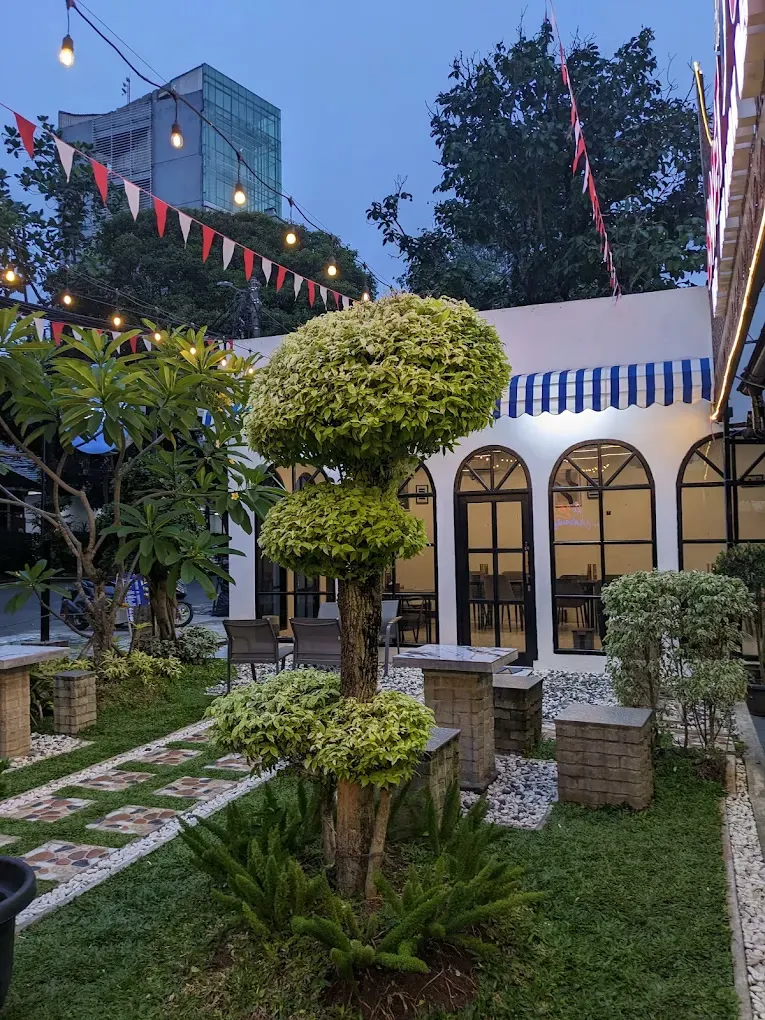 Area outdoor berupa taman hijau dengan bendera hias di depan bangunan Baraso